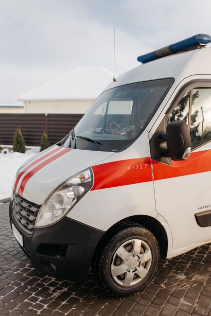 The image shows the rear section of a white commercial van parked on a city street. Three large blue rubbish bags made of plastic are placed on the pavement immediately behind the van, with two bags l